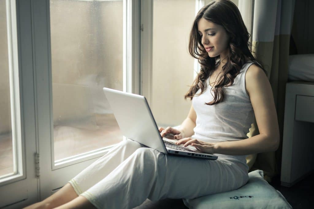 femme assise à près d'une fenêtre sur son ordinateur
